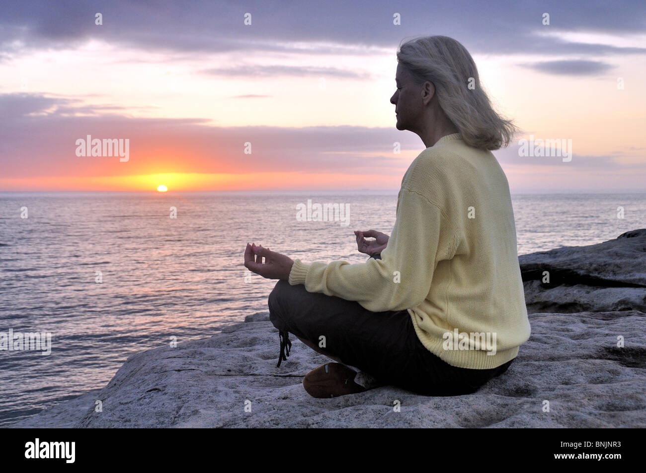 Méditer rêver Ciel Océan mer plage de rochers hauts Woman Relax Coucher du soleil lever du soleil la méditation personne mature Banque D'Images