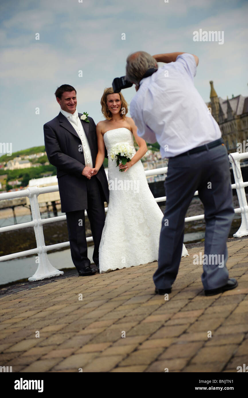 Un photographe de mariage photos de la mariée et le marié sur la promenade, Aberystwyth Wales UK Banque D'Images