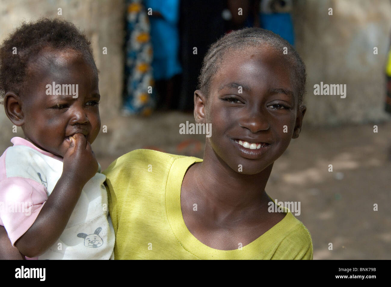 Afrique, Sénégal, Dakar. Village Wolof, le plus grand groupe ethnique du Sénégal, principalement les agriculteurs et pêcheurs. Jeune fille avec bébé. Banque D'Images