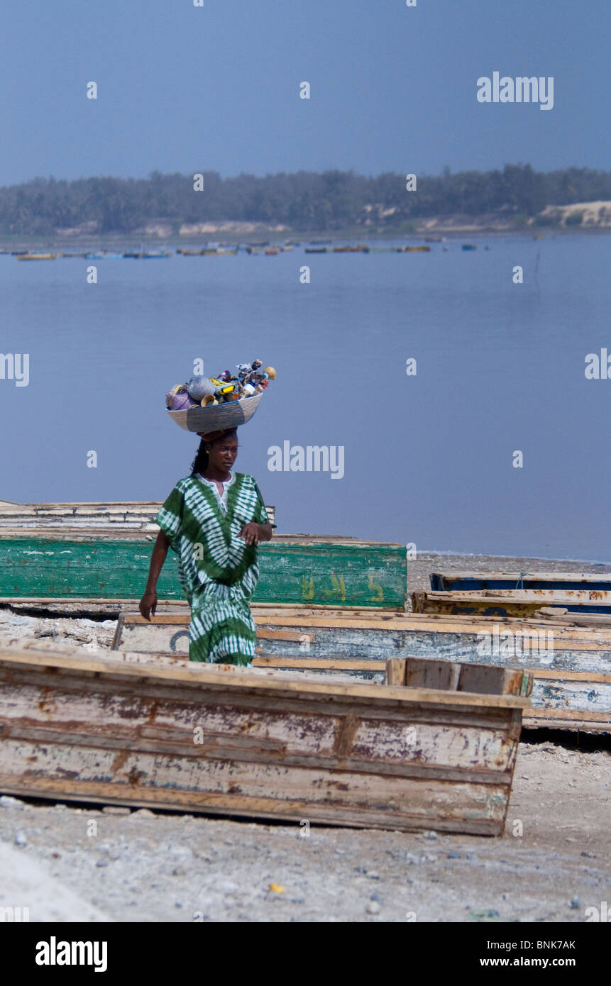 Afrique, Sénégal, Dakar. Le Lac Rose de Retba. La collecte de sel des bateaux sur le Lac Retba. Vendeur femelle avec panier de poupées de souvenirs. Banque D'Images