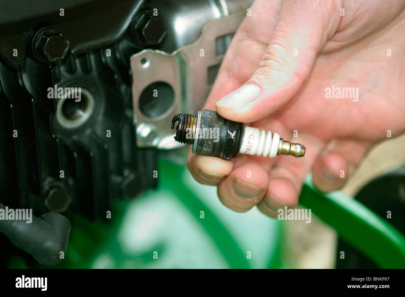 Retrait et vérification sur la bougie d'un moteur à essence de la faucheuse rotative Banque D'Images Retrait et vérification sur la bougie d'un moteur à essence de la faucheuse rotative Banque D'Images