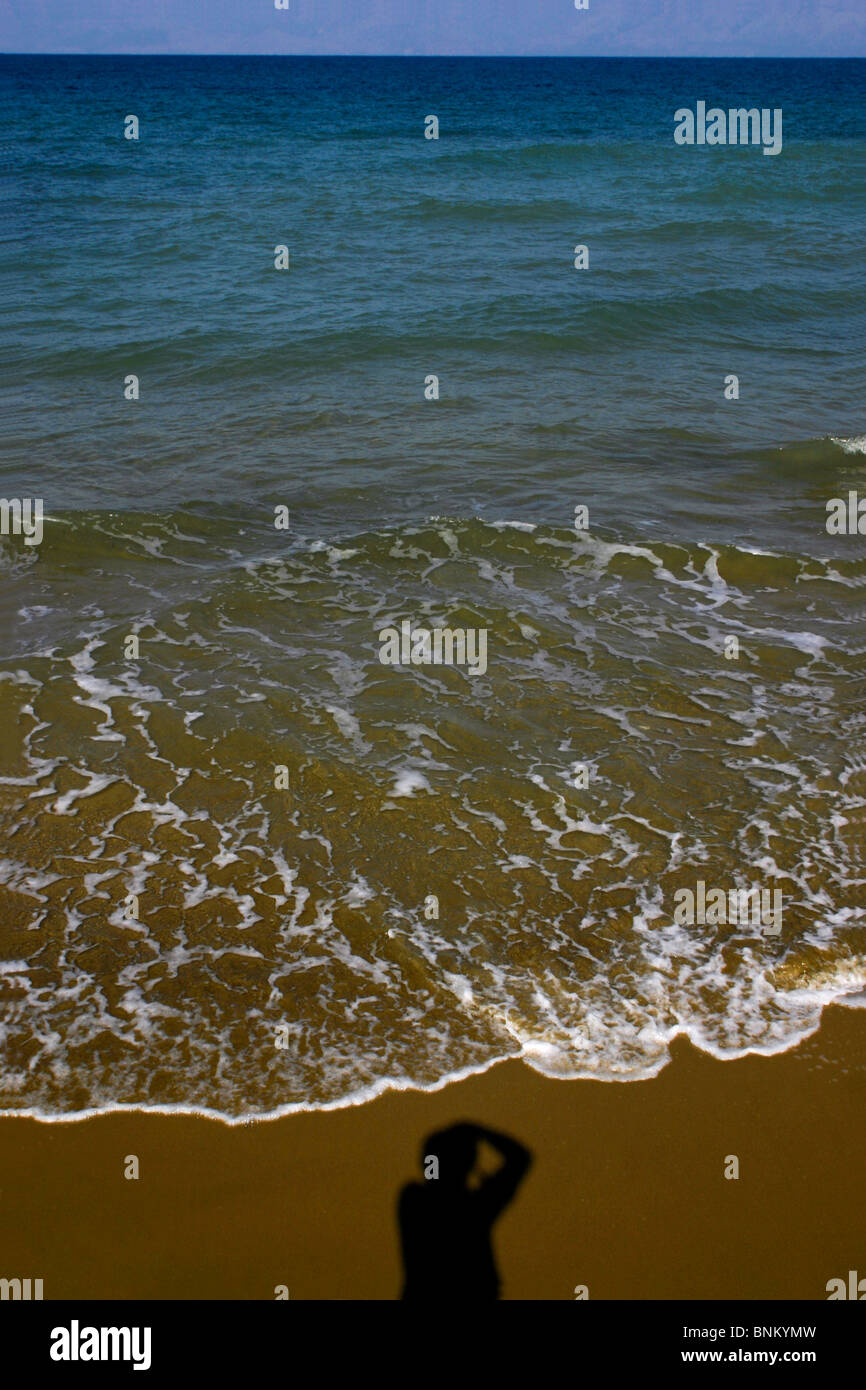 Silhouette d'une personne de prendre une photo sur la plage par une journée ensoleillée avec eux face à la mer. Banque D'Images