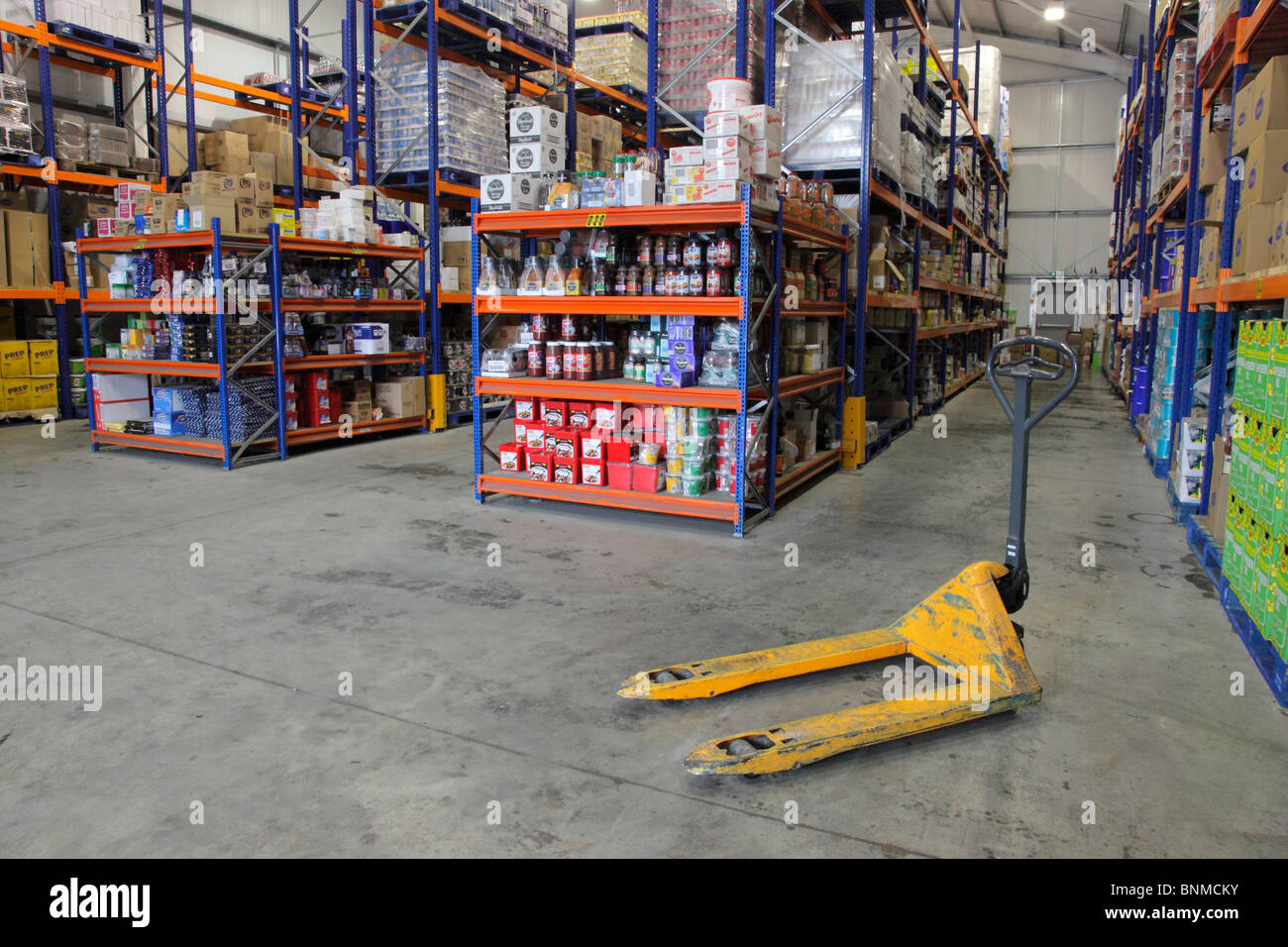 Un transpalette jaune dans un entrepôt de produits secs d'une société de distribution alimentaire Banque D'Images