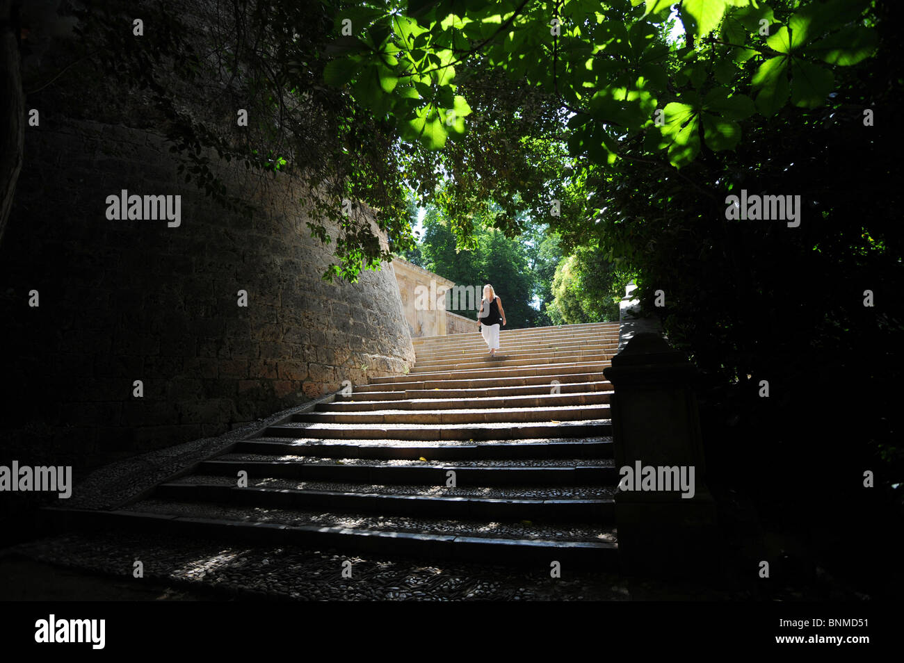 Une femme marche dans les étapes tout en prenant une promenade autour de l'extérieur des murs de l'Alhambra Banque D'Images