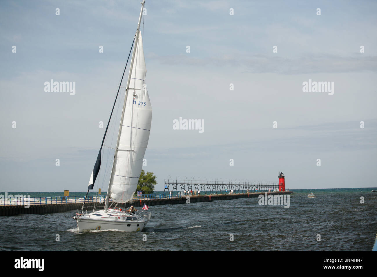 Voile bateau navigue le long de la jetée et le phare du lac Michigan dans la rivière Black à South Haven Michigan Banque D'Images