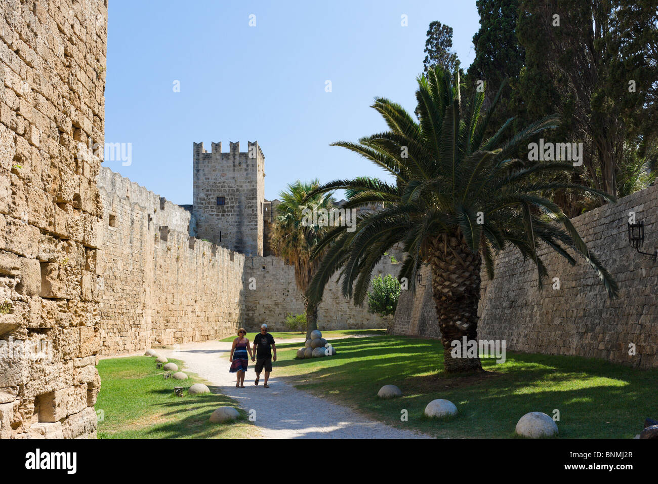 Couple en train de marcher le long du chemin dans le fossé médiéval autour des murs de la vieille ville, la ville de Rhodes, Rhodes, Grèce Banque D'Images