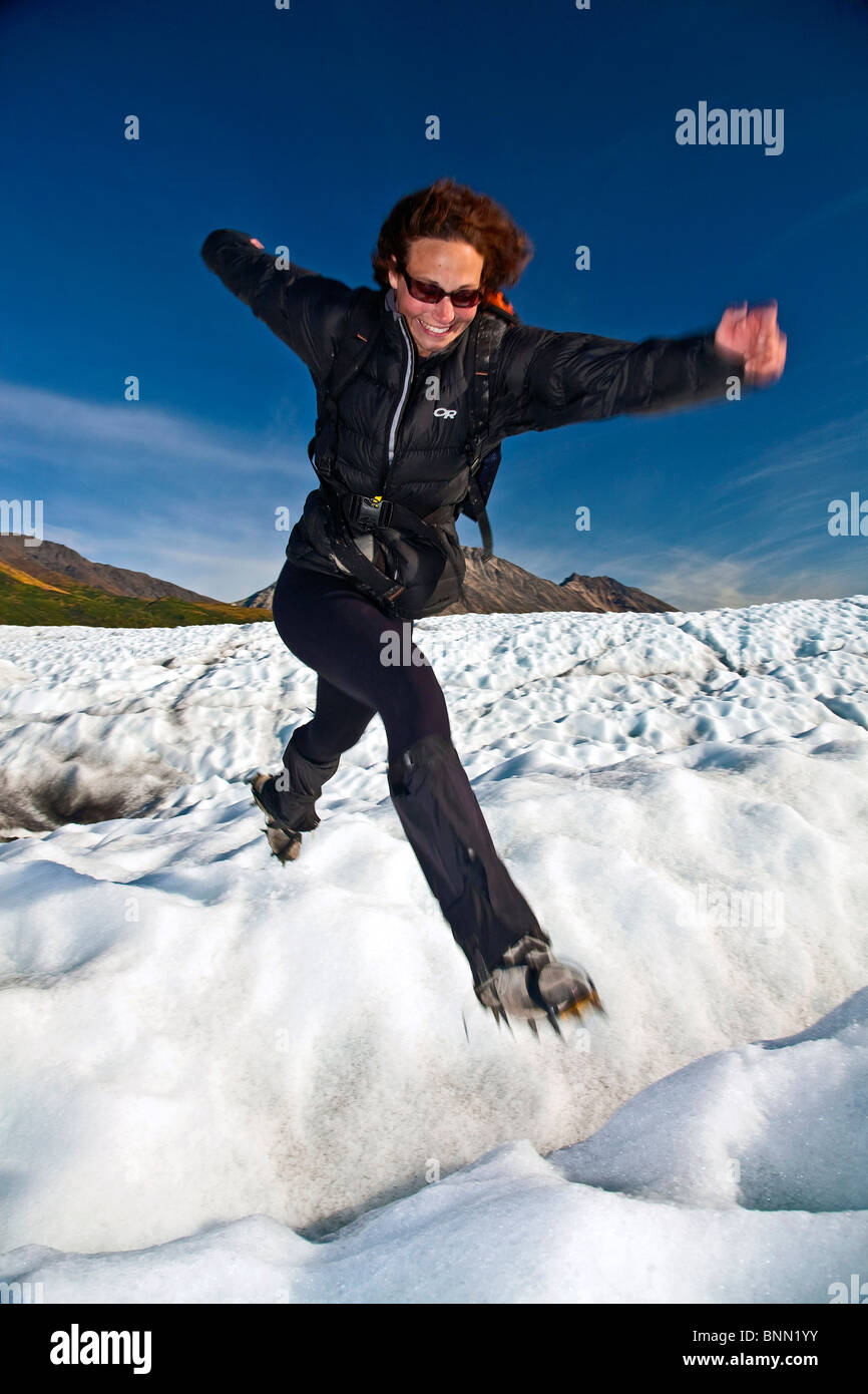 Femme sautant à travers une crevasse sur le glacier racine tandis que sur une journée de randonnée dans le parc national Wrangell-St.Elias, Alaska Banque D'Images