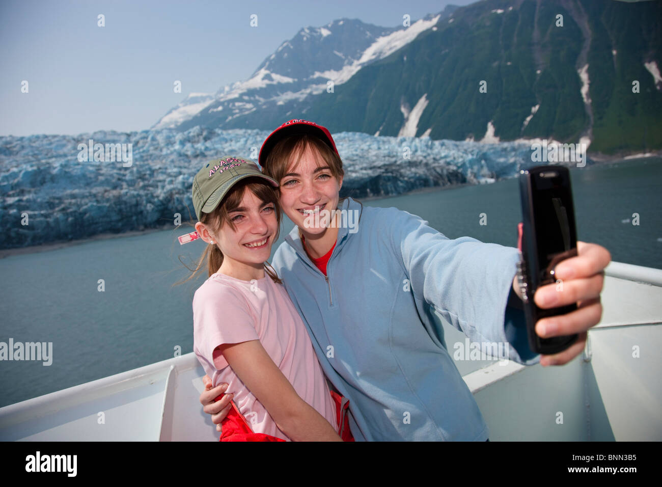 Les sœurs de prendre des photos d'eux-mêmes avec un téléphone cellulaire près du glacier Harriman, Prince William Sound, Alaska Banque D'Images