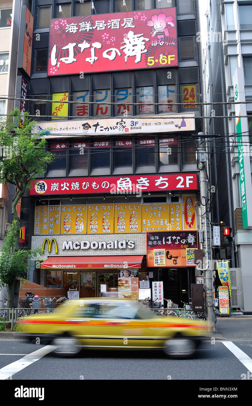 McDonald's restaurants japonais et dans le même bâtiment avec taxi jaune passant par [flou] (Tokyo, Japon) Banque D'Images