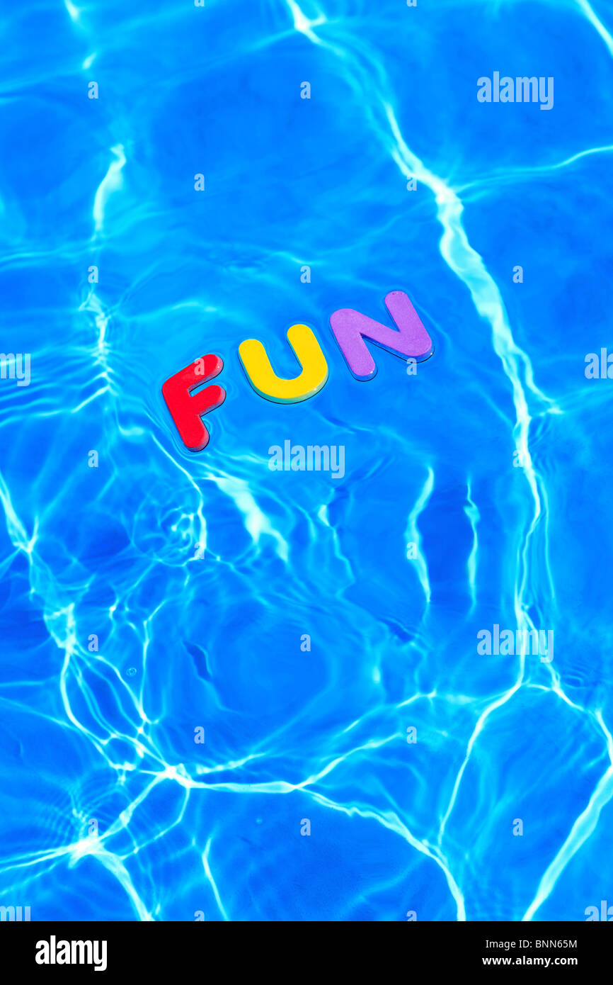 Plaisir du jeu en mousse lettres flottant à la surface de l'eau d'une piscine Banque D'Images