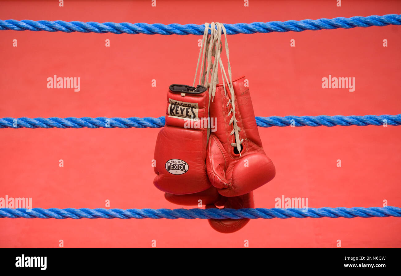 Gants de boxe rouge accrocher sur les cordes d'un ring de boxe. Photo par James Boardman Banque D'Images