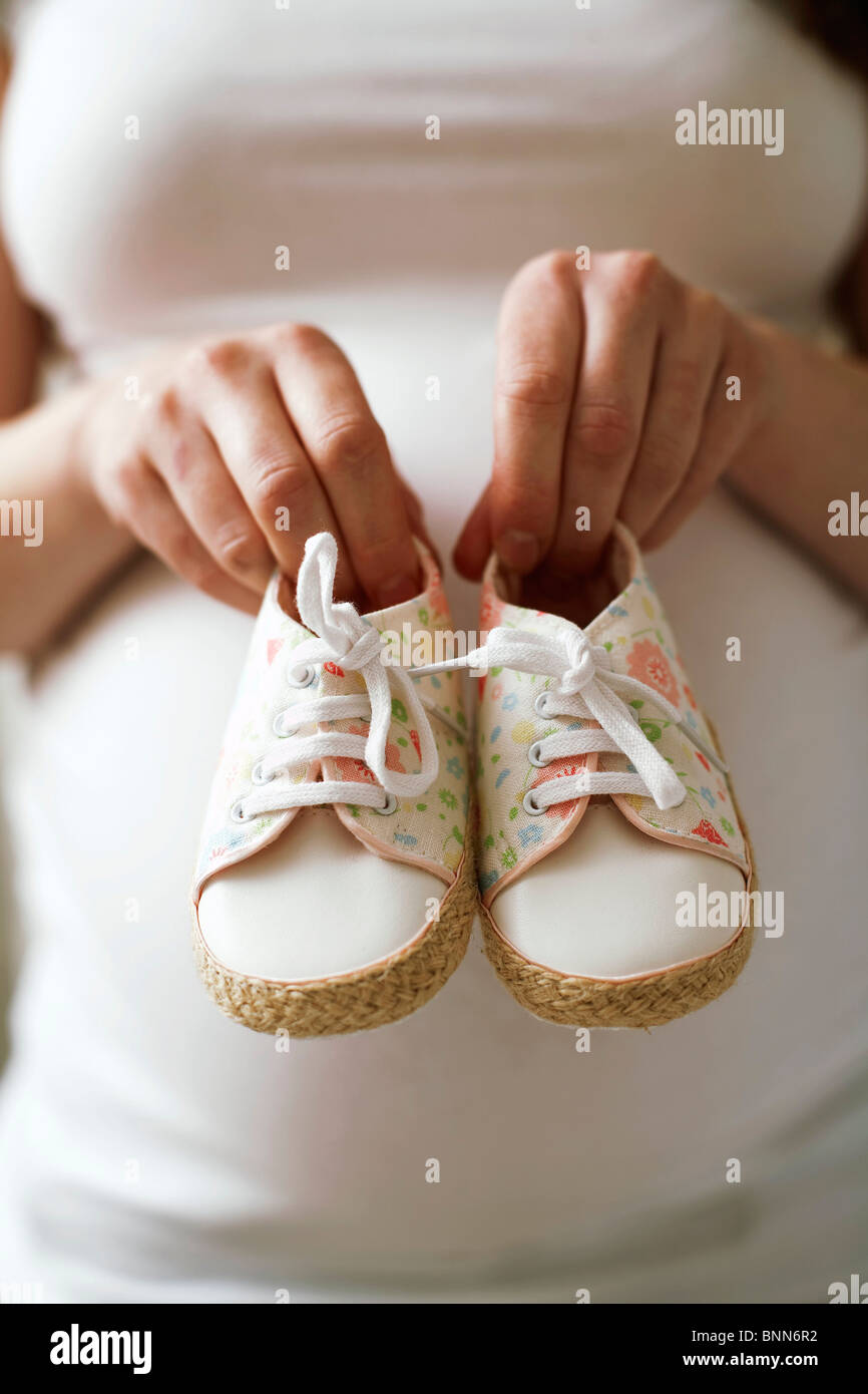 Pregnant woman holding baby shoes Banque D'Images