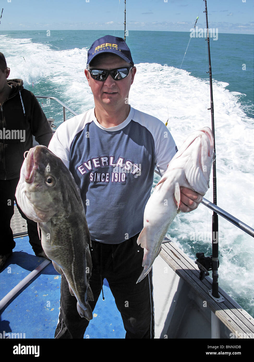 Le sport de la pêche en haute mer. Un homme montre ses prises de deux de la morue. Banque D'Images