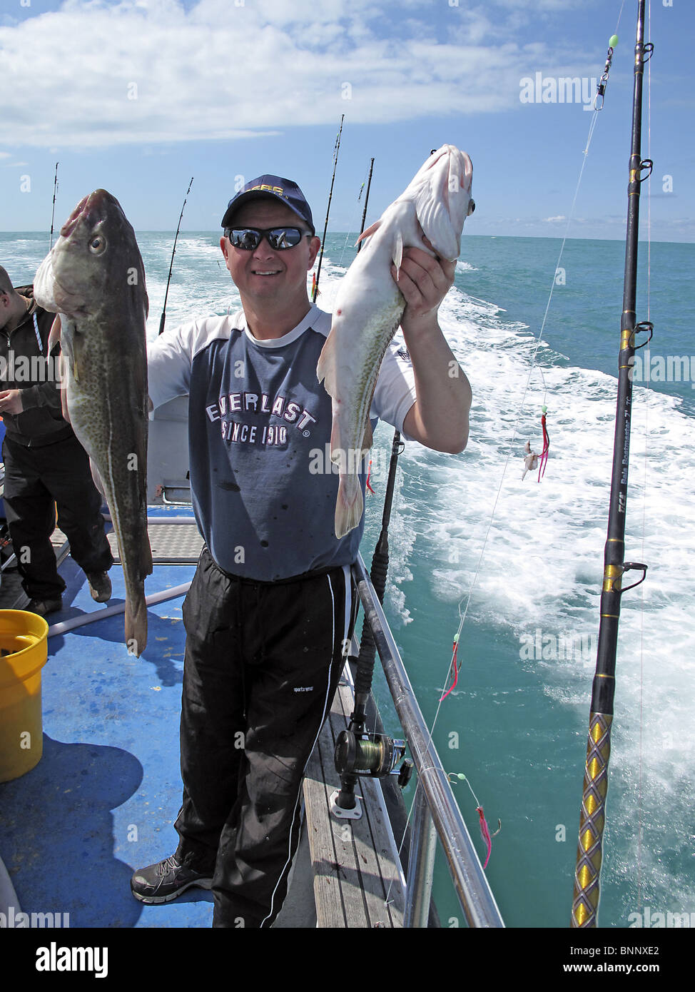 Le sport de la pêche en haute mer. Un homme montre ses prises de deux de la morue. Banque D'Images