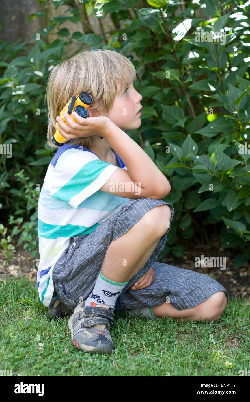 Boy (5-7) les oiseaux dans le jardin. Banque D'Images