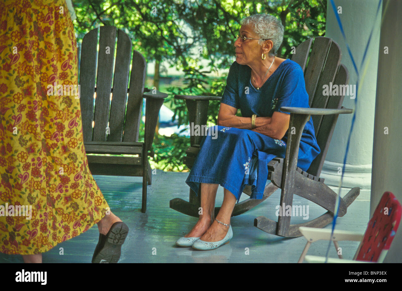 Femme âgée assise sur une chaise à bascule en bois stlye Adirondack Banque D'Images