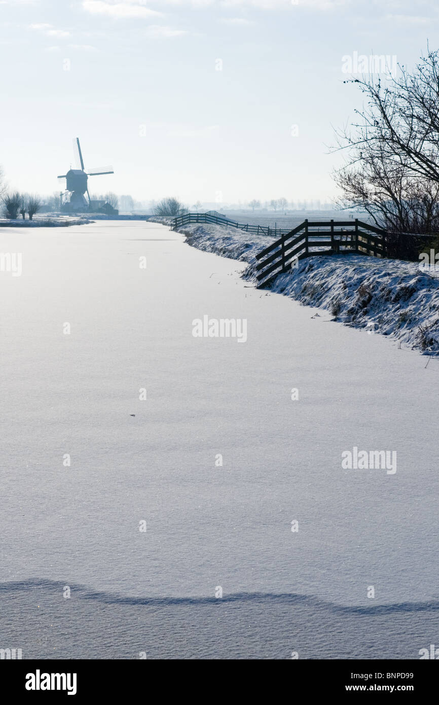 Rivière gelée et moulin à vent en Hollande pendant l'hiver Banque D'Images