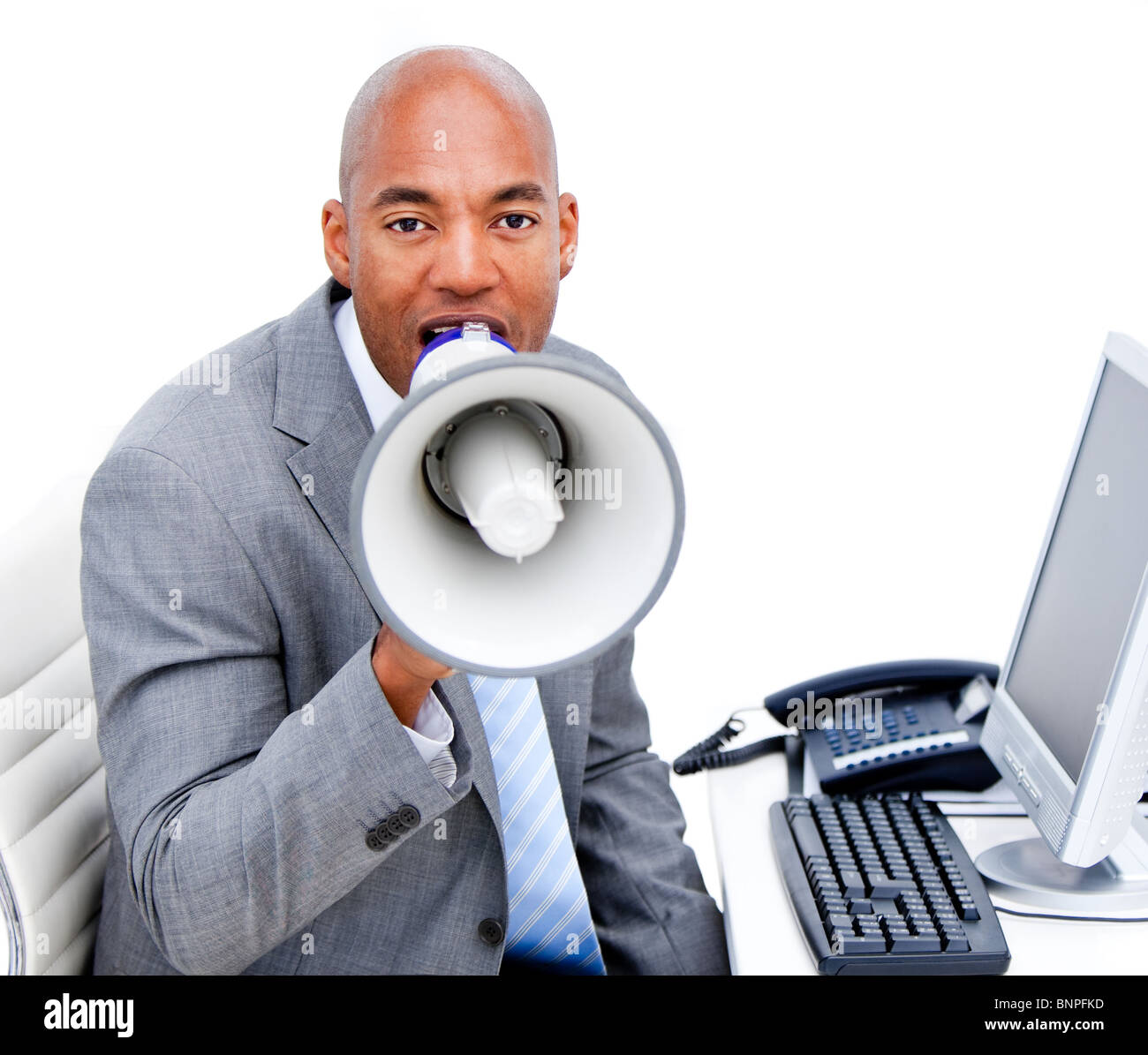 Businessman yelling furieux avec un porte-voix, assis sur son bureau Banque D'Images