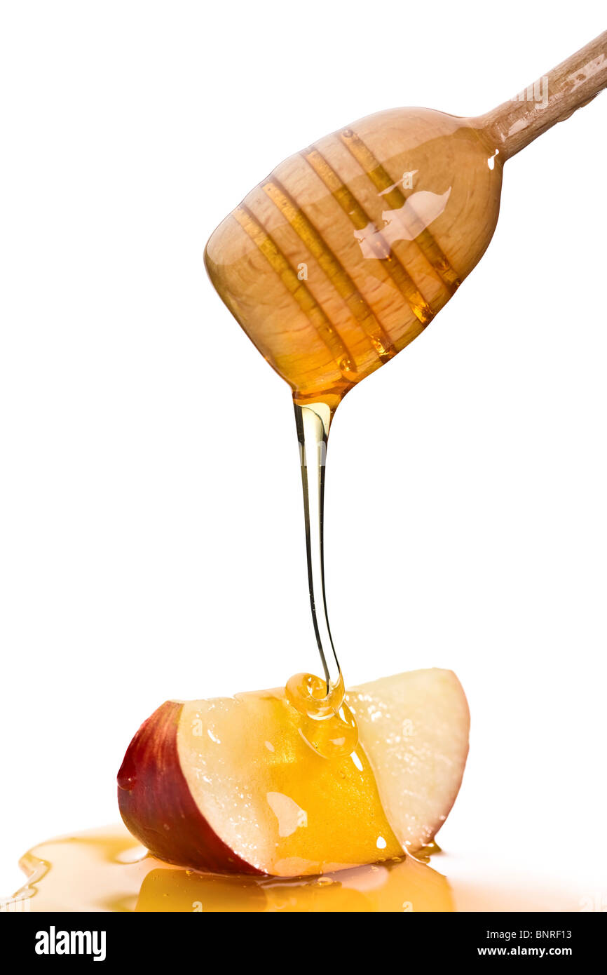 Verser le miel sur une tranche de pomme rouge avec un miel goutteur (isolé contre blanc) Banque D'Images