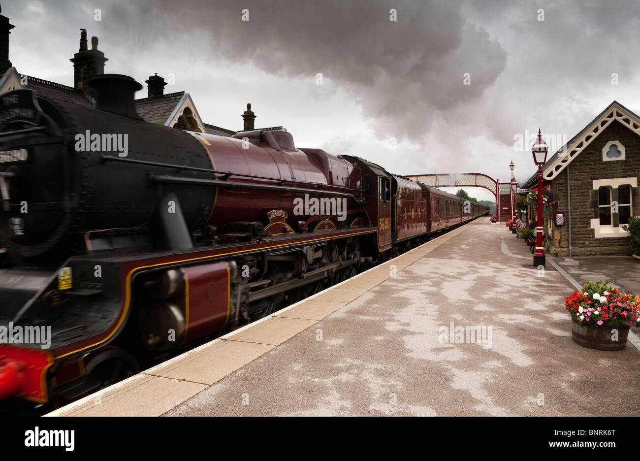 Un train à vapeur en passant par une gare ferroviaire Banque D'Images