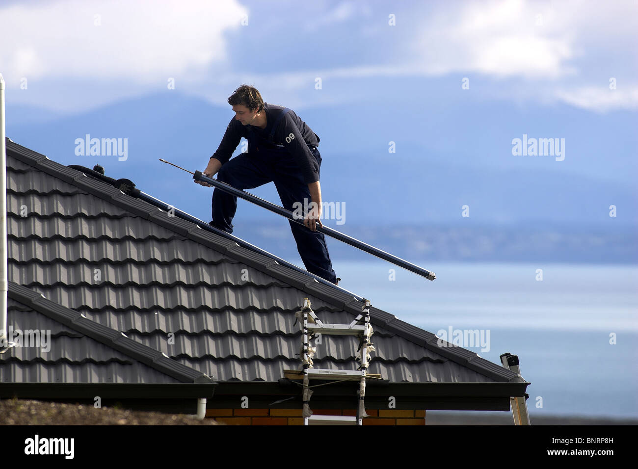 Artisan qualifié l'installation de chauffe-eau solaire pour une maison, Nelson, Nouvelle-Zélande, la ville ayant le plus grand ensoleillement Banque D'Images