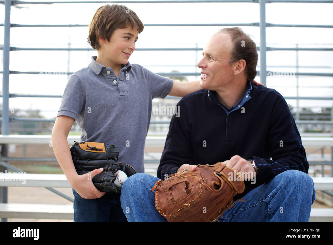 Garçon regarde son père dès qu'il pratique le baseball au parc. Banque D'Images Garçon regarde son père dès qu'il pratique le baseball au parc. Banque D'Images
