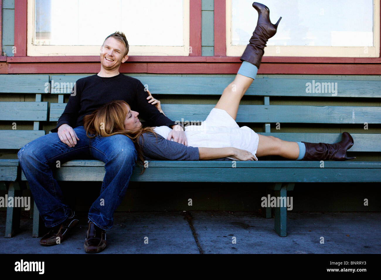 Couple est assis sur un banc et sourire. Banque D'Images Couple est assis sur un banc et sourire. Banque D'Images