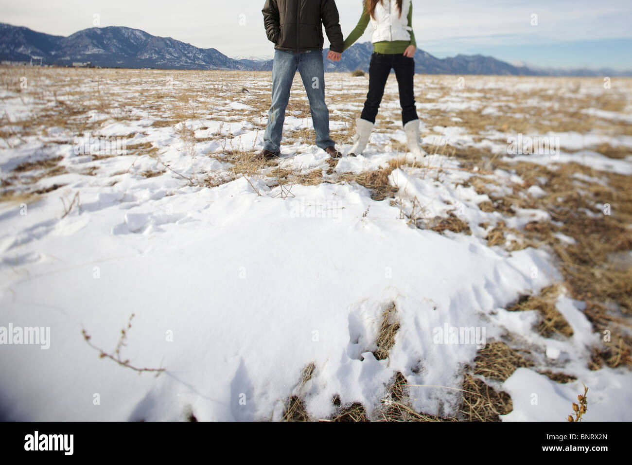 Couple holding hands and looking away in a snowy, champ ouvert. Banque D'Images Couple holding hands and looking away in a snowy, champ ouvert. Banque D'Images