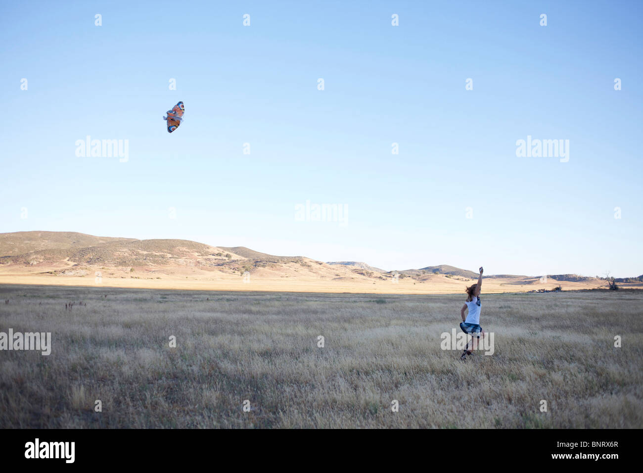 Jeune femme vole un cerf-volant dans un champ ouvert. Banque D'Images Jeune femme vole un cerf-volant dans un champ ouvert. Banque D'Images
