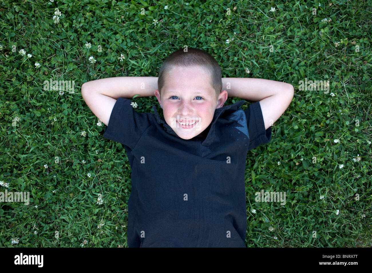 Jeune garçon jette dans l'herbe et sourit. Banque D'Images Jeune garçon jette dans l'herbe et sourit. Banque D'Images