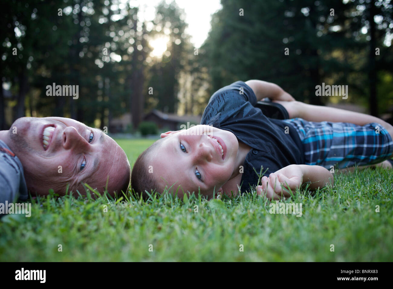 Jeune garçon jette dans l'herbe avec son père et sourit. Banque D'Images Jeune garçon jette dans l'herbe avec son père et sourit. Banque D'Images