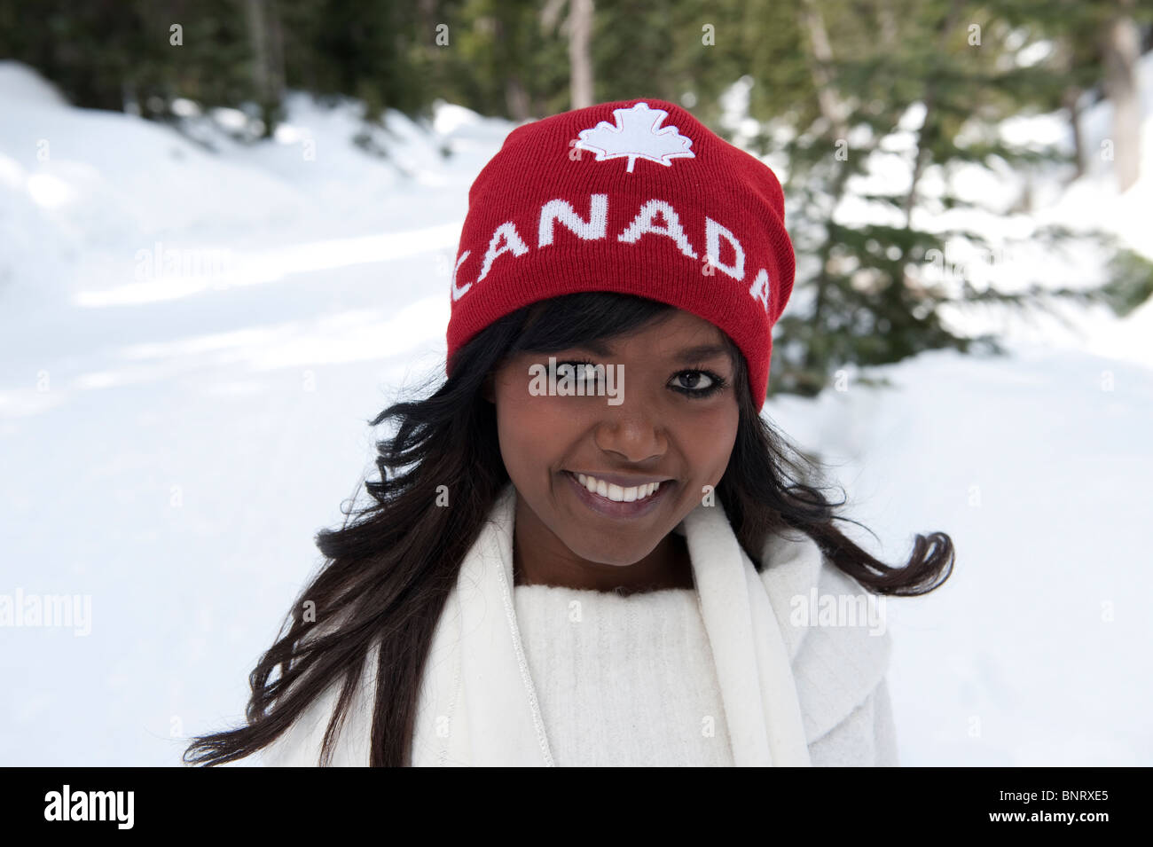 Portrait of a young African American Woman wearing a red hat canada avec l'arrière-plan de neige. Banque D'Images