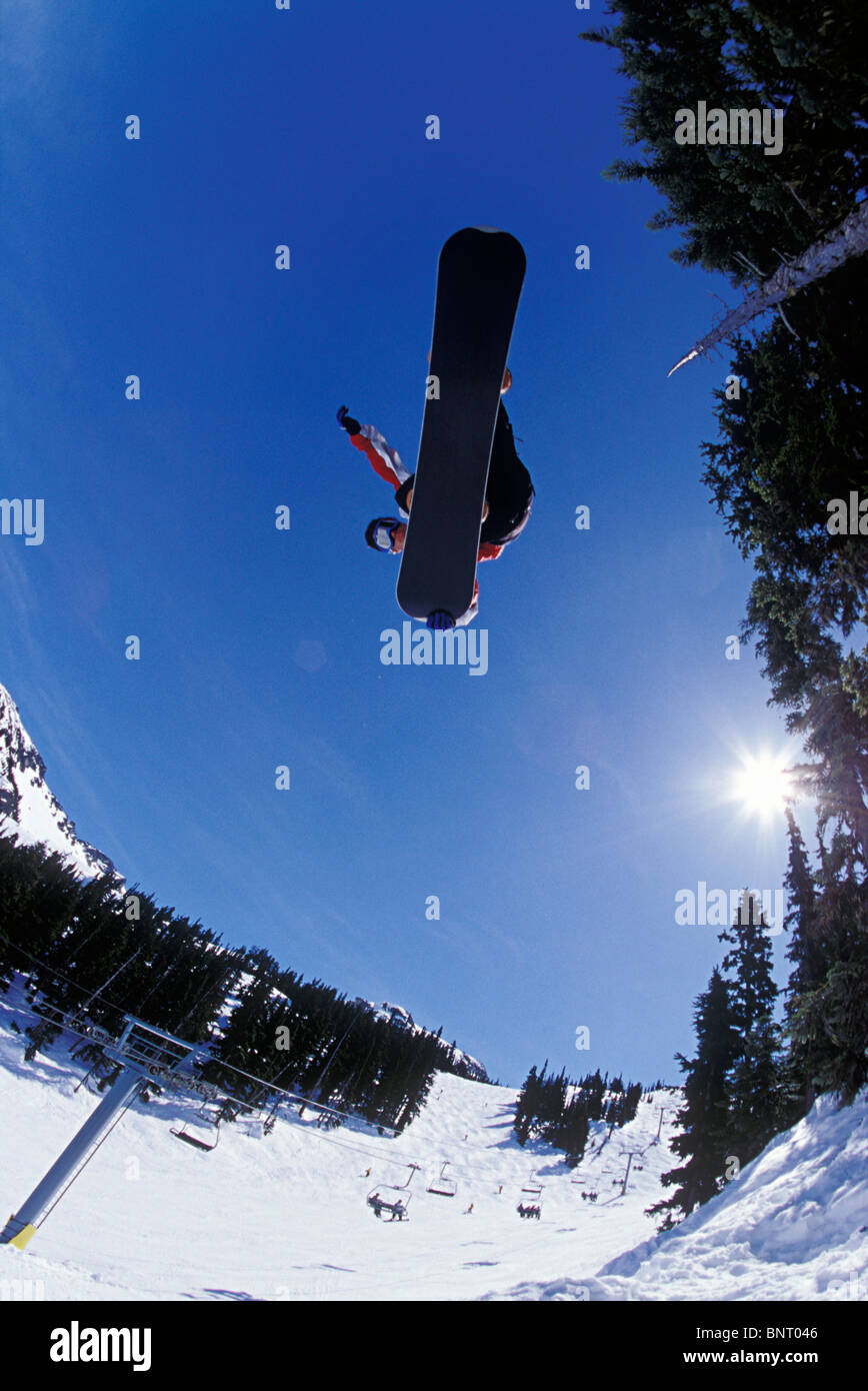 Vue fisheye de snowboarder sautant au-dessus de télésiège. Banque D'Images