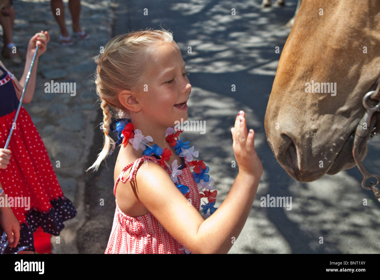 5-6 ans girl petting horse en Juillet 4ème jour de l'indépendance Parade. © Myrleen Pearson Banque D'Images