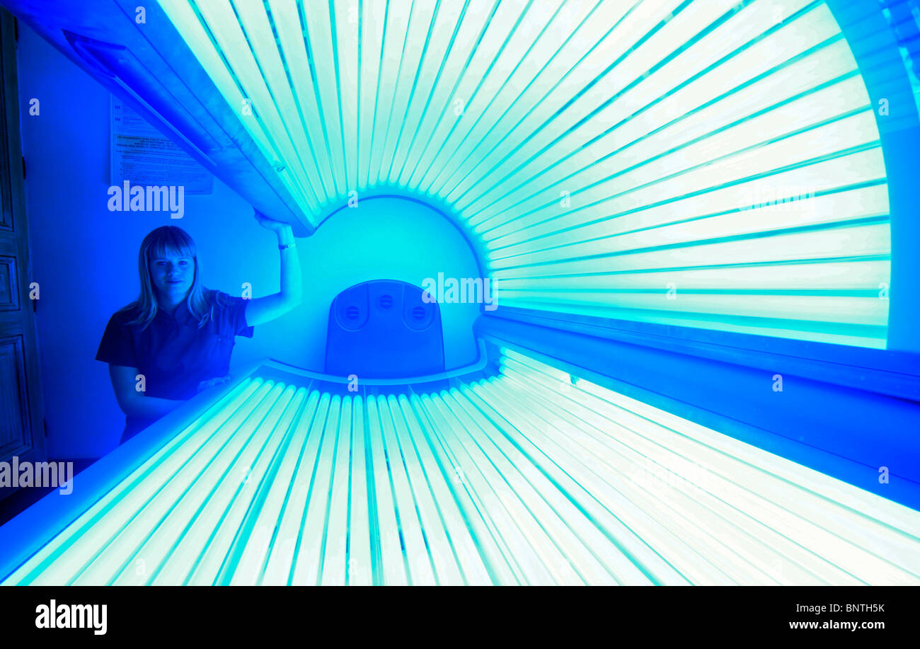 Un employé dans un institut de beauté pose avec le solarium Banque D'Images