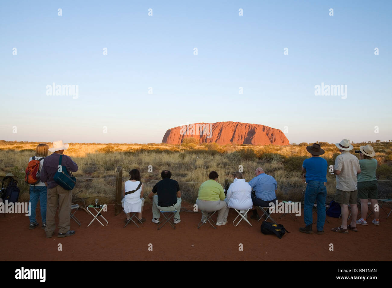 Les touristes se rassemblent pour regarder le coucher du soleil sur Uluru (Ayers Rock). Le Parc National d'Uluru-Kata Tjuta, Territoire du Nord, Australie. Banque D'Images
