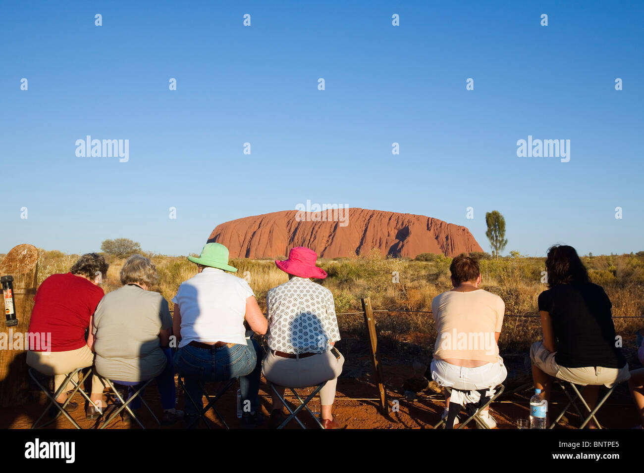 Les touristes regarder le coucher du soleil sur Uluru (Ayers Rock). Le Parc National d'Uluru-Kata Tjuta, Territoire du Nord, Australie. Banque D'Images