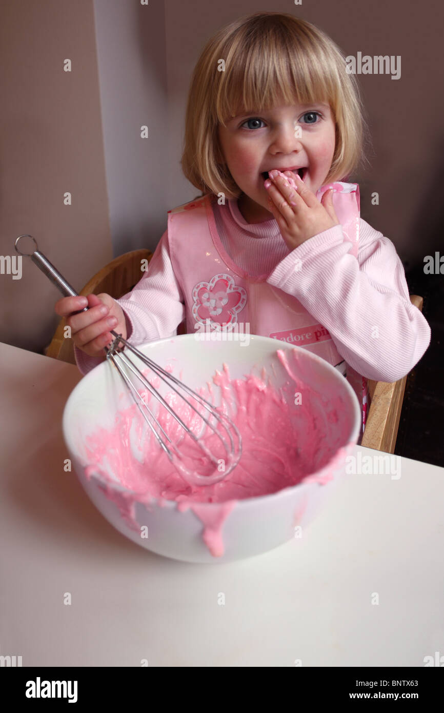 Petite fille rose cerise à partir de la dégustation d'un bol à mélanger. Banque D'Images