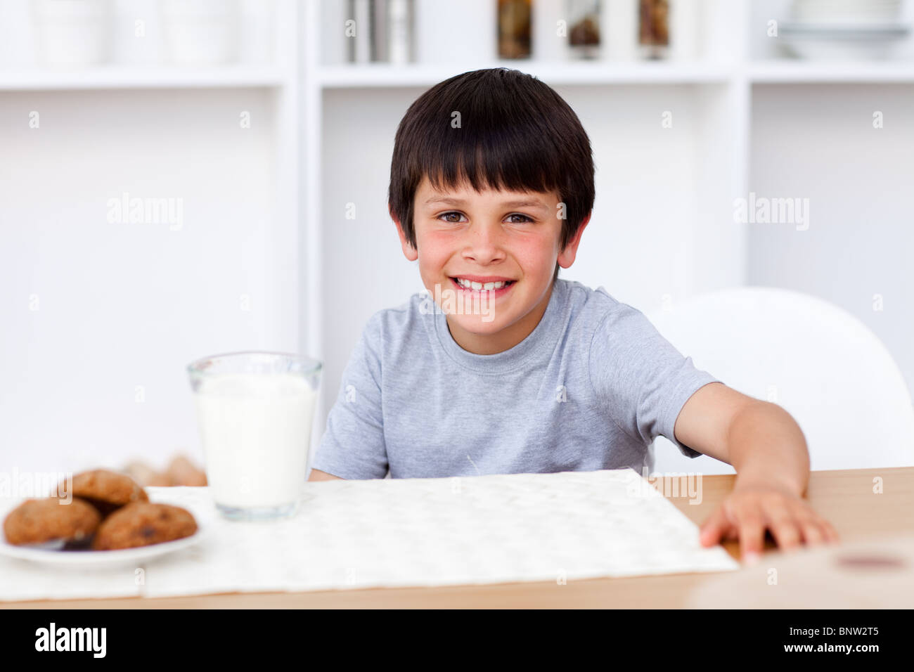 Smiling boy manger des biscuits et boire du lait Banque D'Images