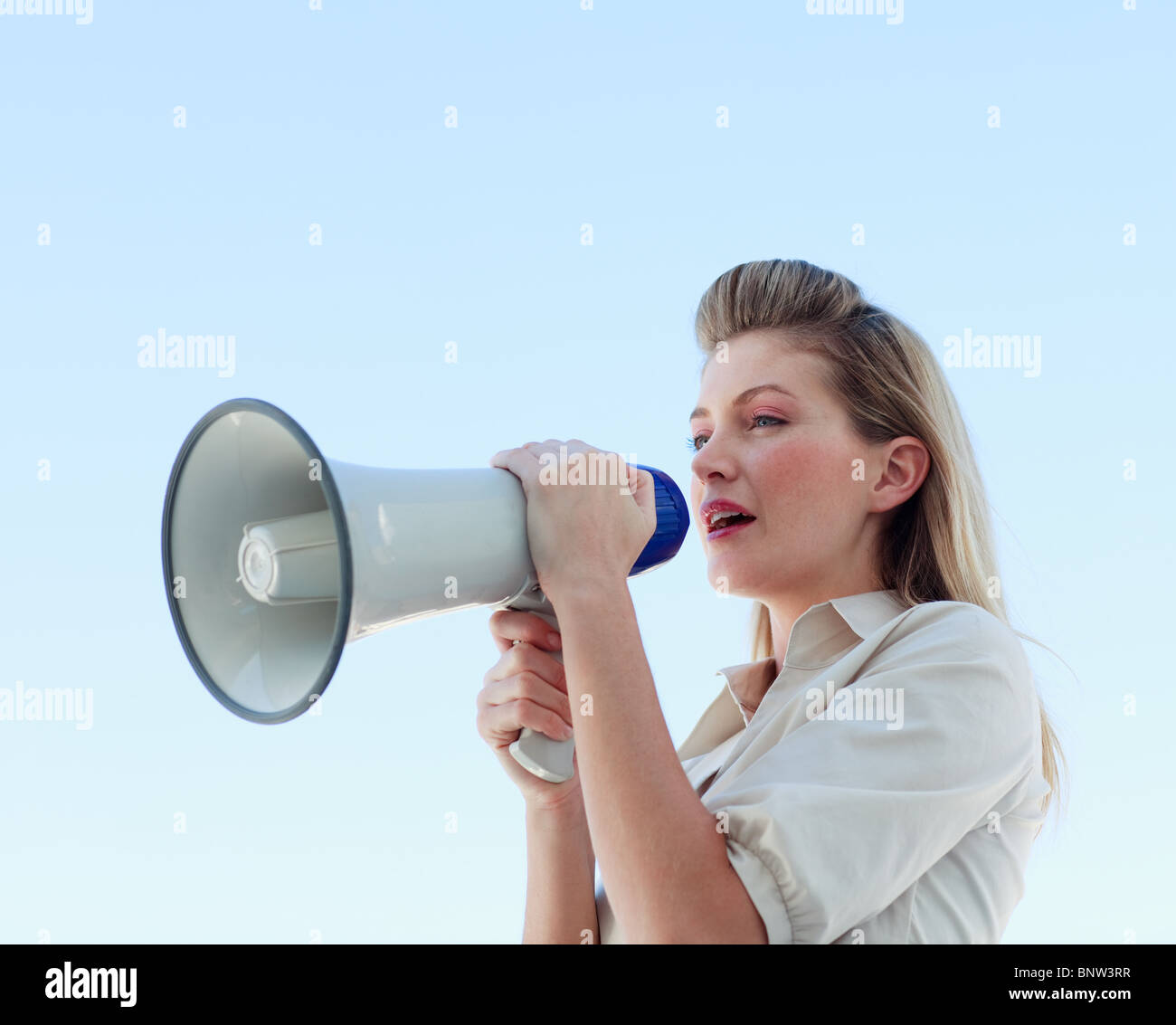 Blond businesswoman crier par mégaphone Banque D'Images