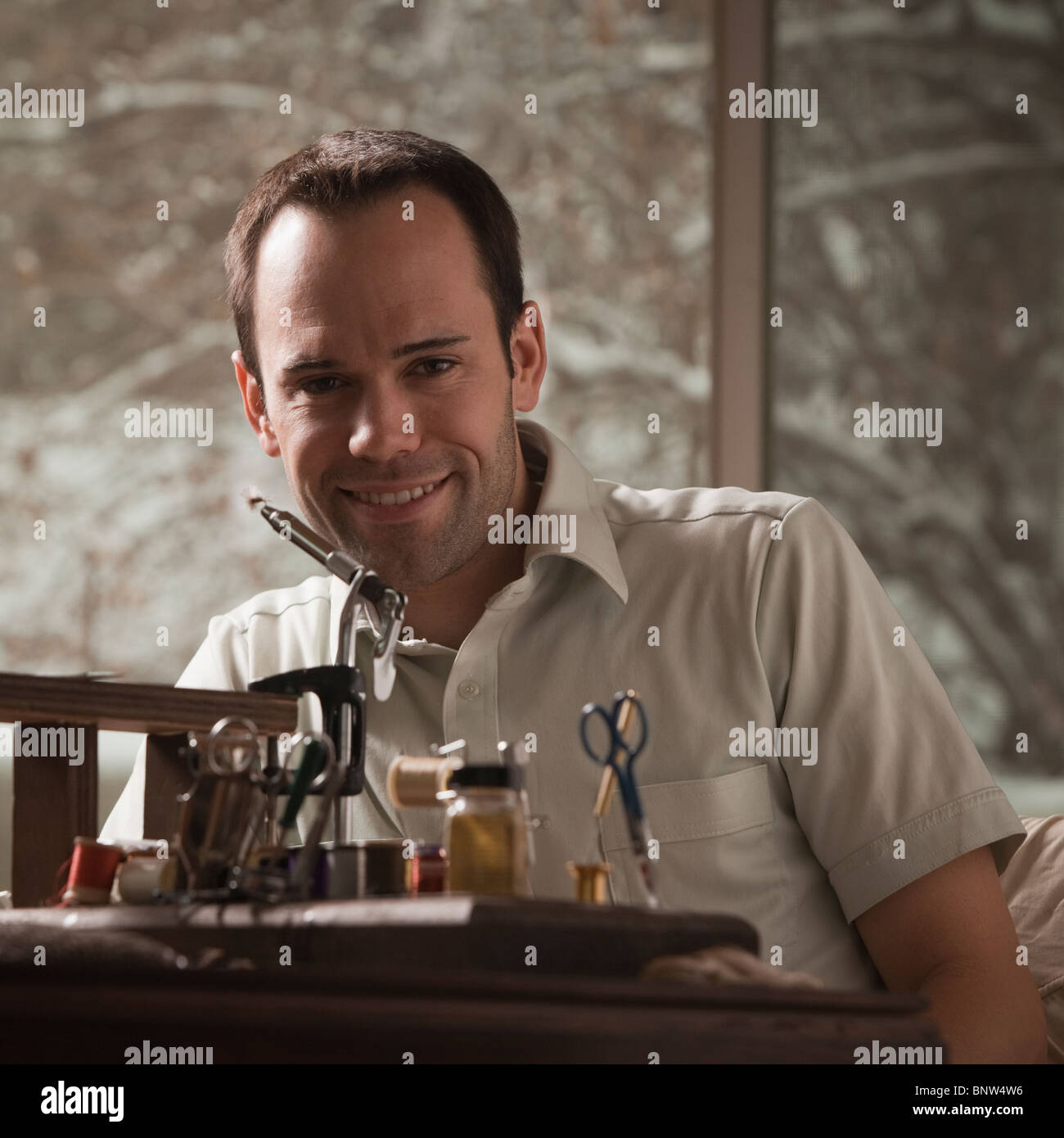 Homme assis derrière la réparation d'équipements de pêche Banque D'Images