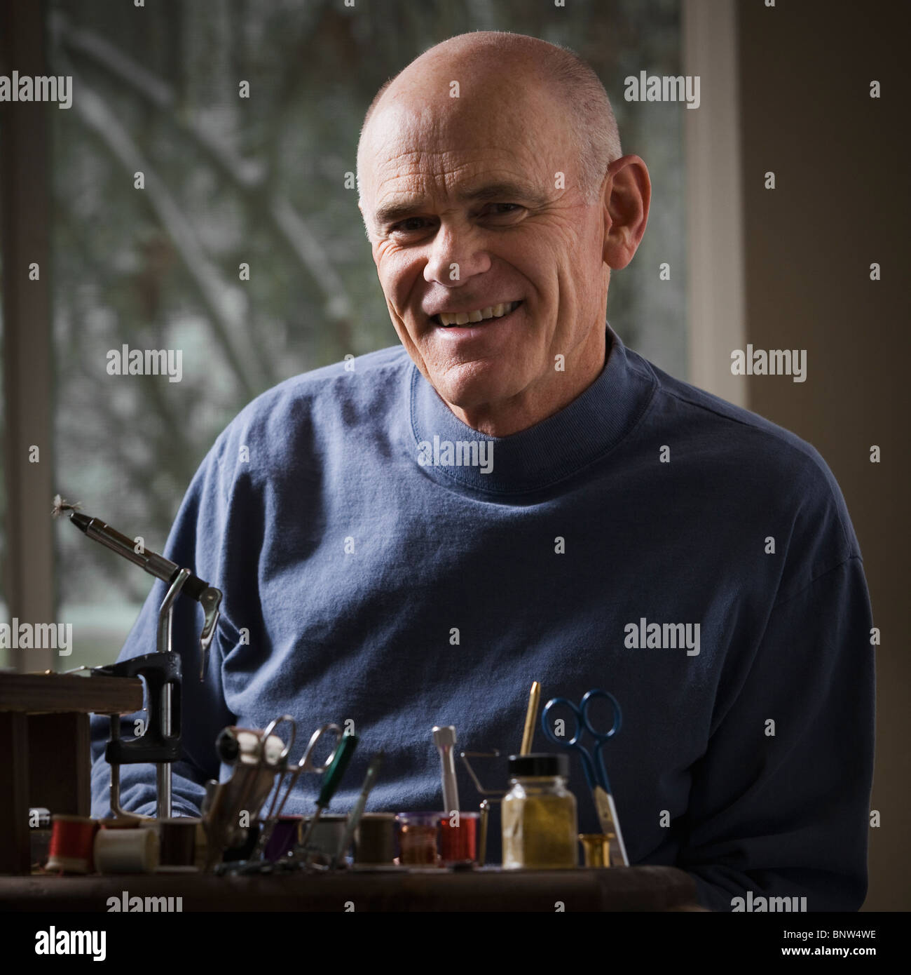 Homme assis derrière l'équipement de réparation des engins de pêche Banque D'Images