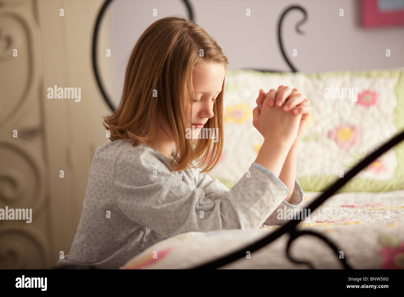 Jeune fille priant avant lit Banque D'Images