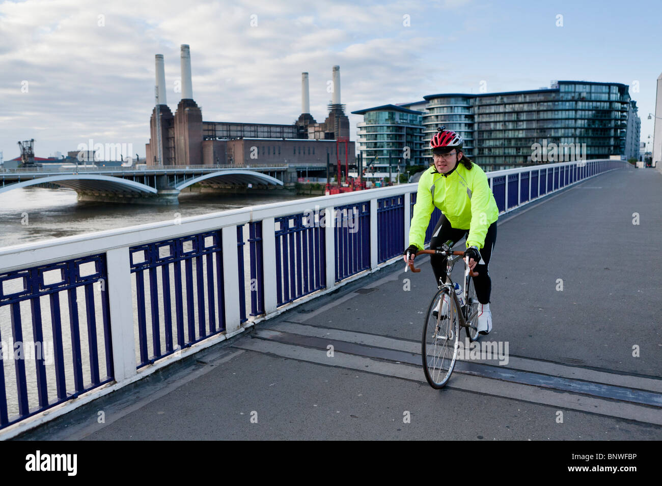 Un cycliste à un gilet réfléchissant passe au-dessus d'un pont sur le trajet nocturne de Londres, Londres, Royaume-Uni Banque D'Images