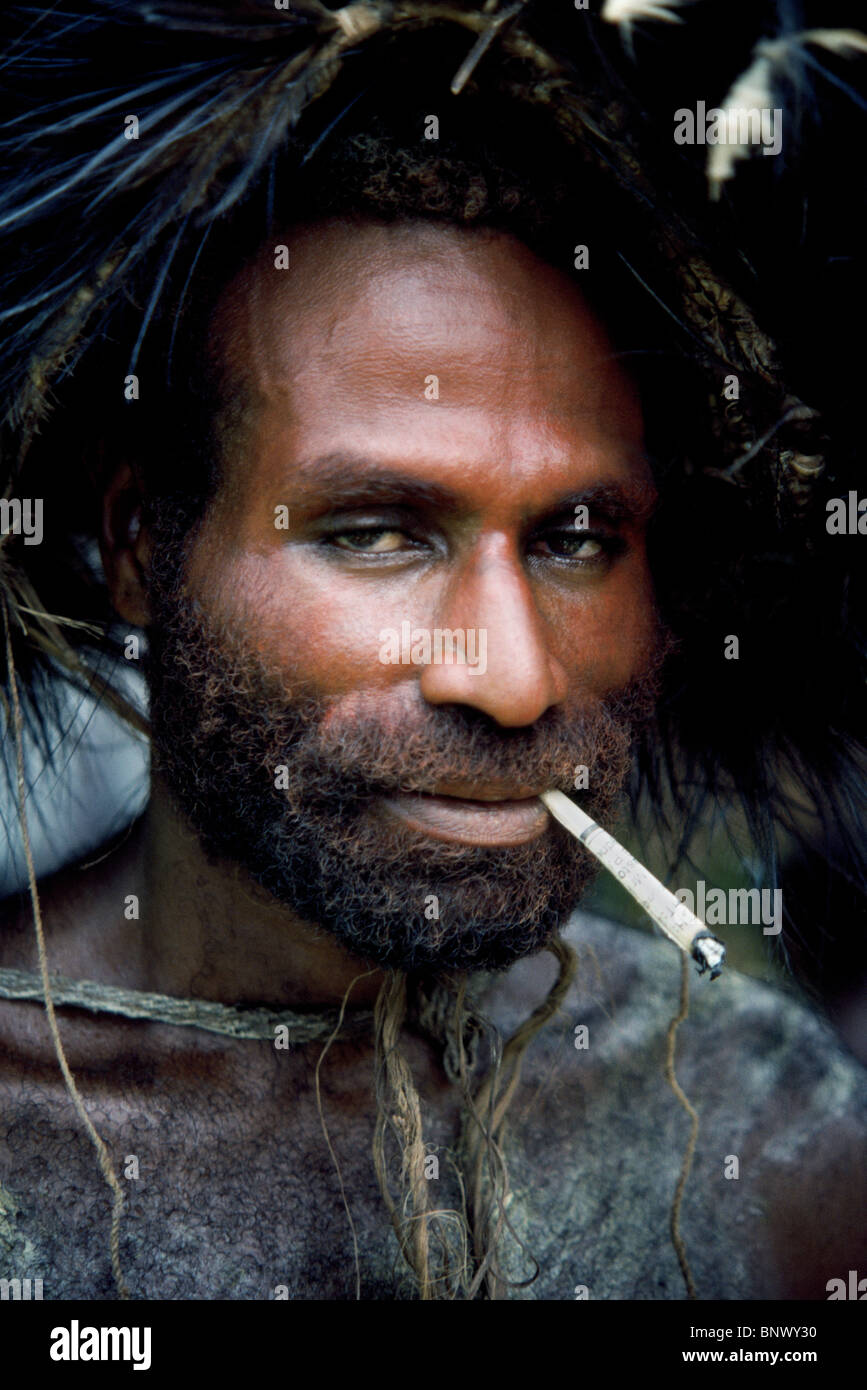 Un homme fume une cigarette il a roulé à la main au cours d'une cérémonie tribale par la rivière Karawari dans East Sepik province de Papouasie Nouvelle Guinée (PNG). Banque D'Images