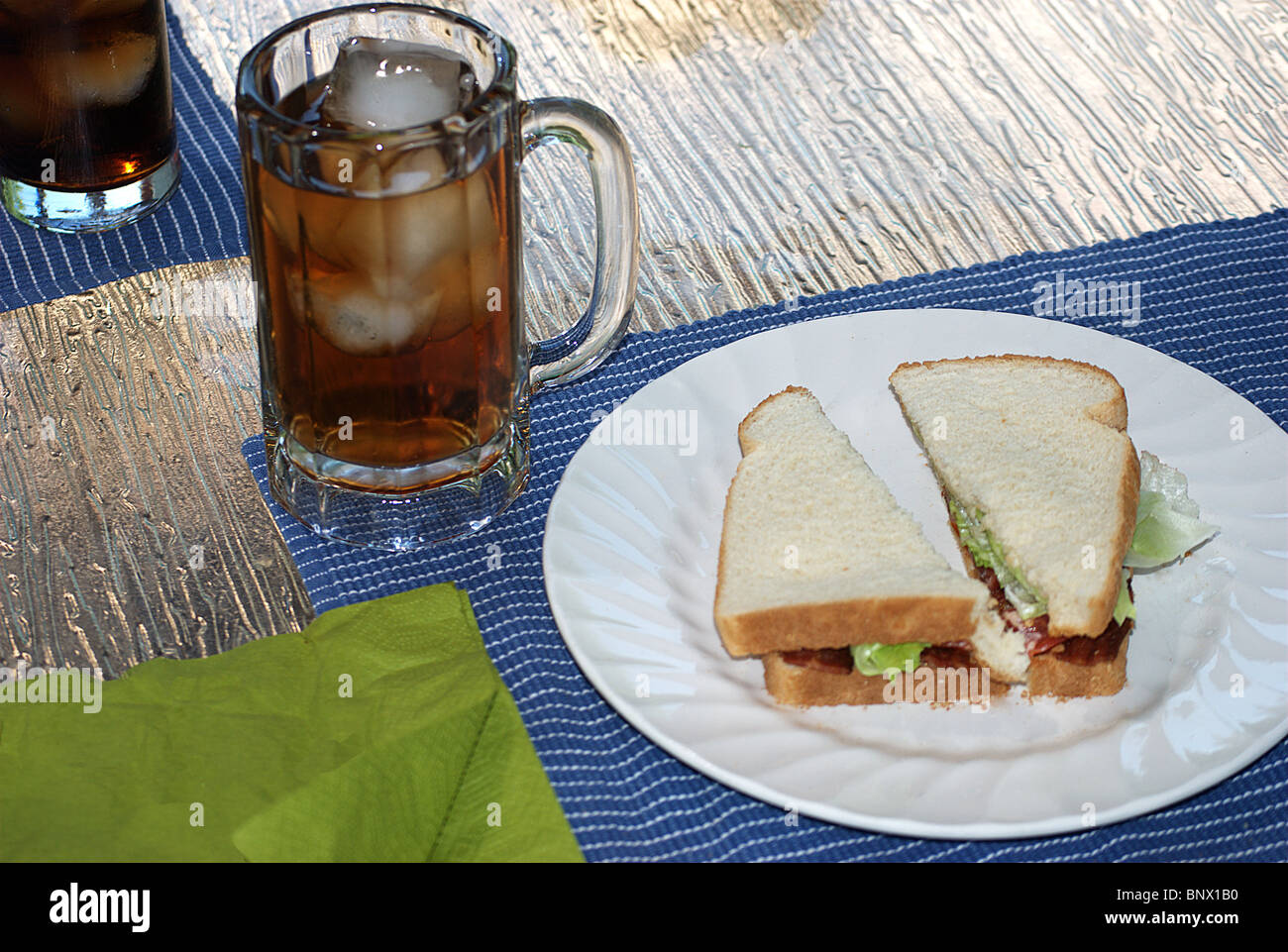 Sandwich tomate et salade au lard et de glace plateau verre sur table patio Banque D'Images