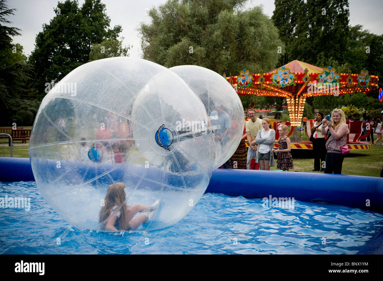 Un jeune enfant marcher sur l'eau à l'intérieur d'un aquabubble dans un parc à Brent à Londres au cours de brent respect festival. Banque D'Images