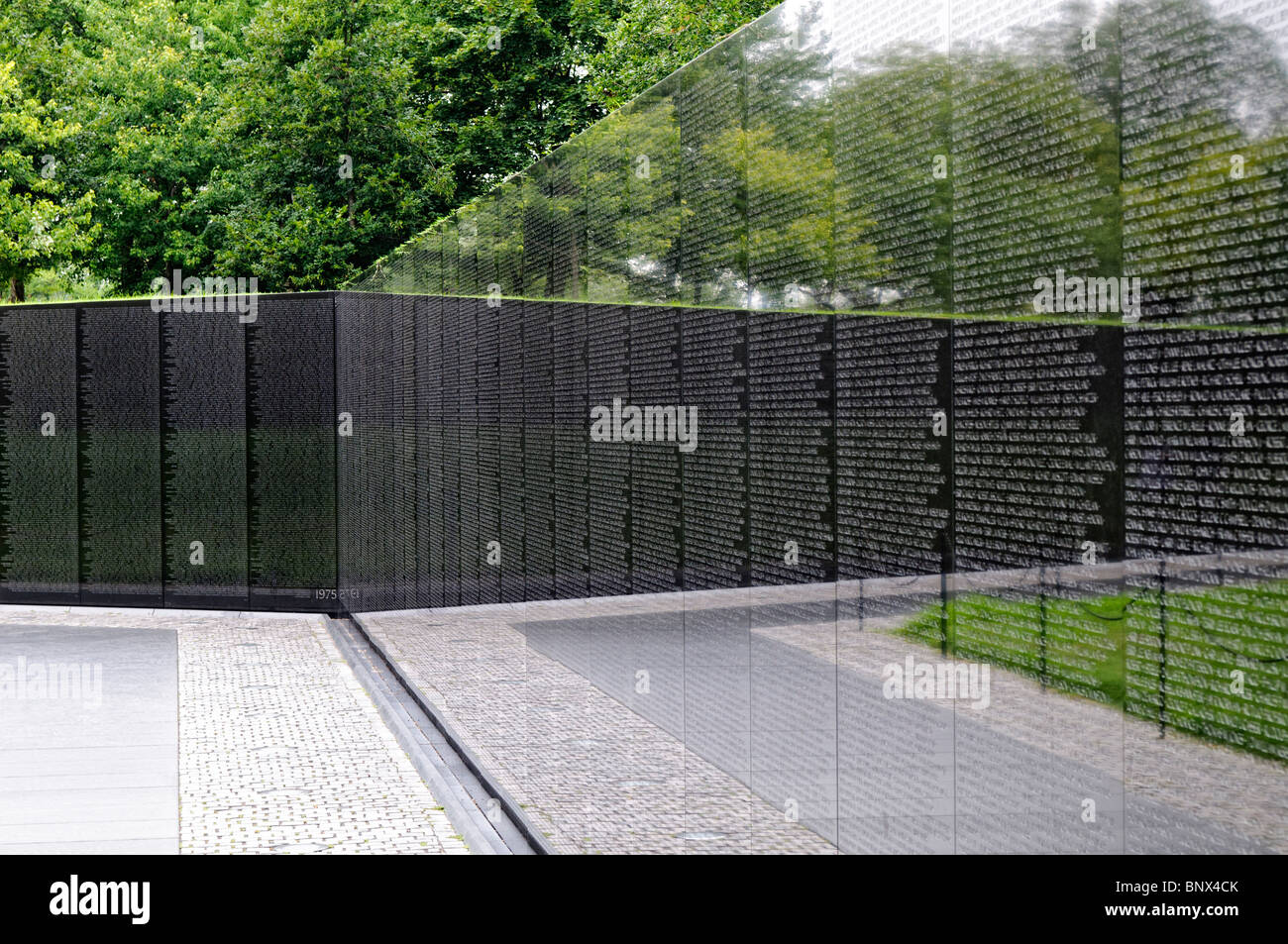 Vietnam Memorial Wall noms Washington DC // WASHINGTON DC — les noms des personnes tuées au combat au Vietnam sont gravés sur le mur du Vietnam Memorial à Washington DC. La surface polie de granit noir reflète les arbres et le ciel environnants, créant une atmosphère poignante et contemplative pour les visiteurs. Banque D'Images