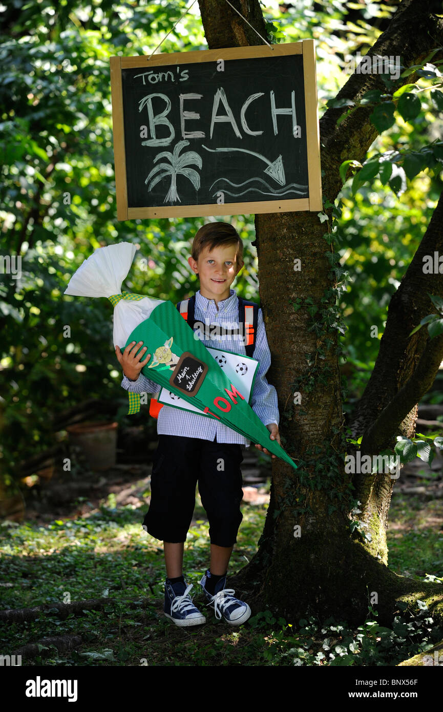 Première journée à l'école. Garçon avec cône en carton dans la cour de l'école. Banque D'Images