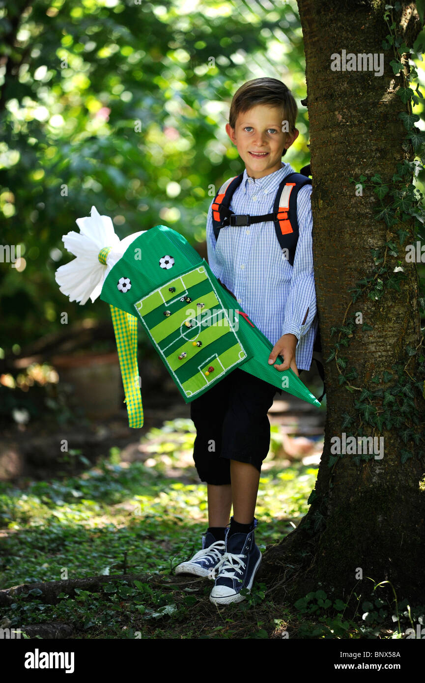 Première journée à l'école. Garçon avec cône en carton dans la cour de l'école. Banque D'Images